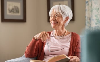 grauhaarige Frau mit Buch auf dem Schoß