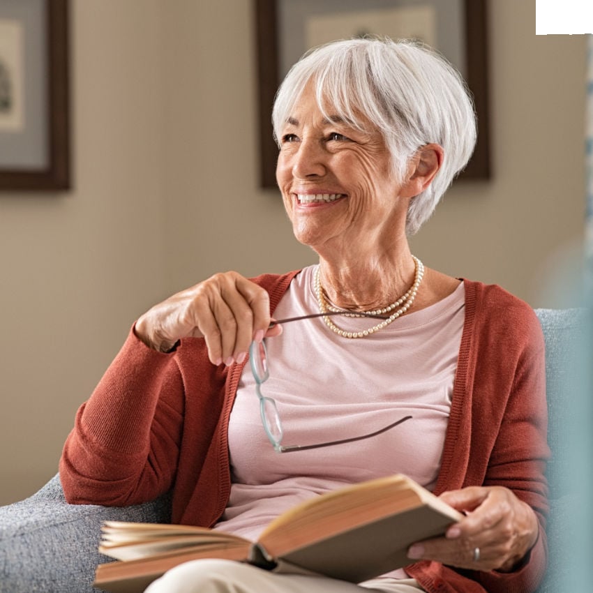 grauhaarige Frau mit Buch auf dem Schoß