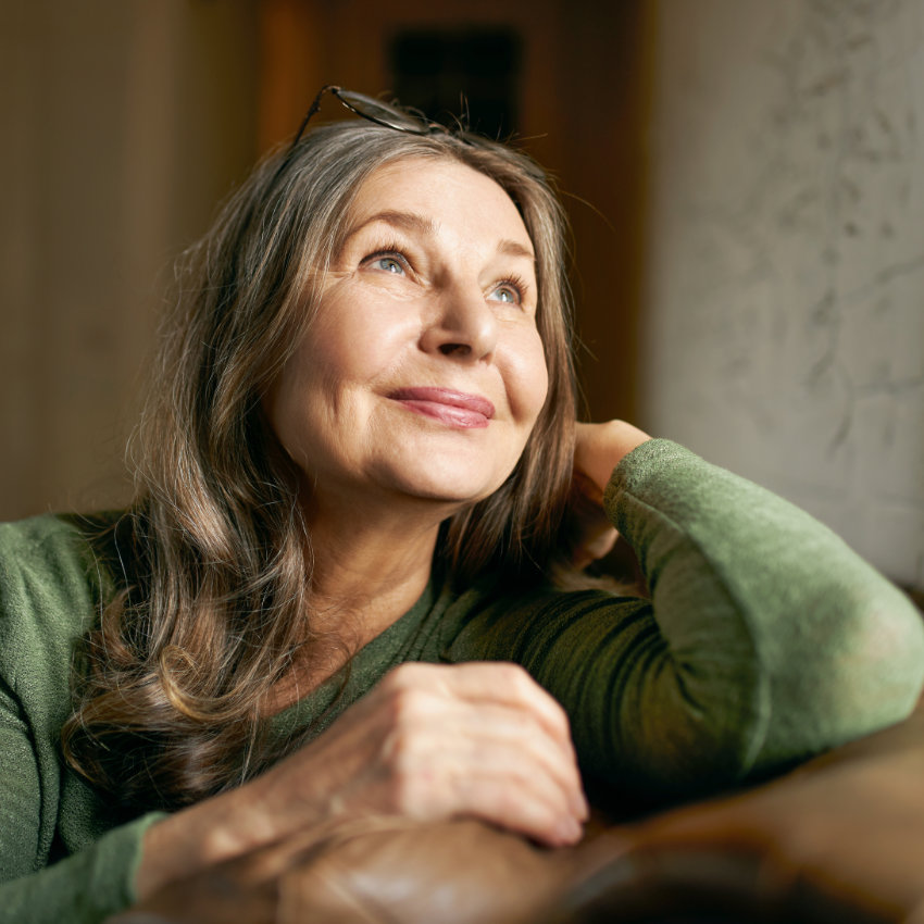 Frau sitzt am Tisch und schaut versonnen