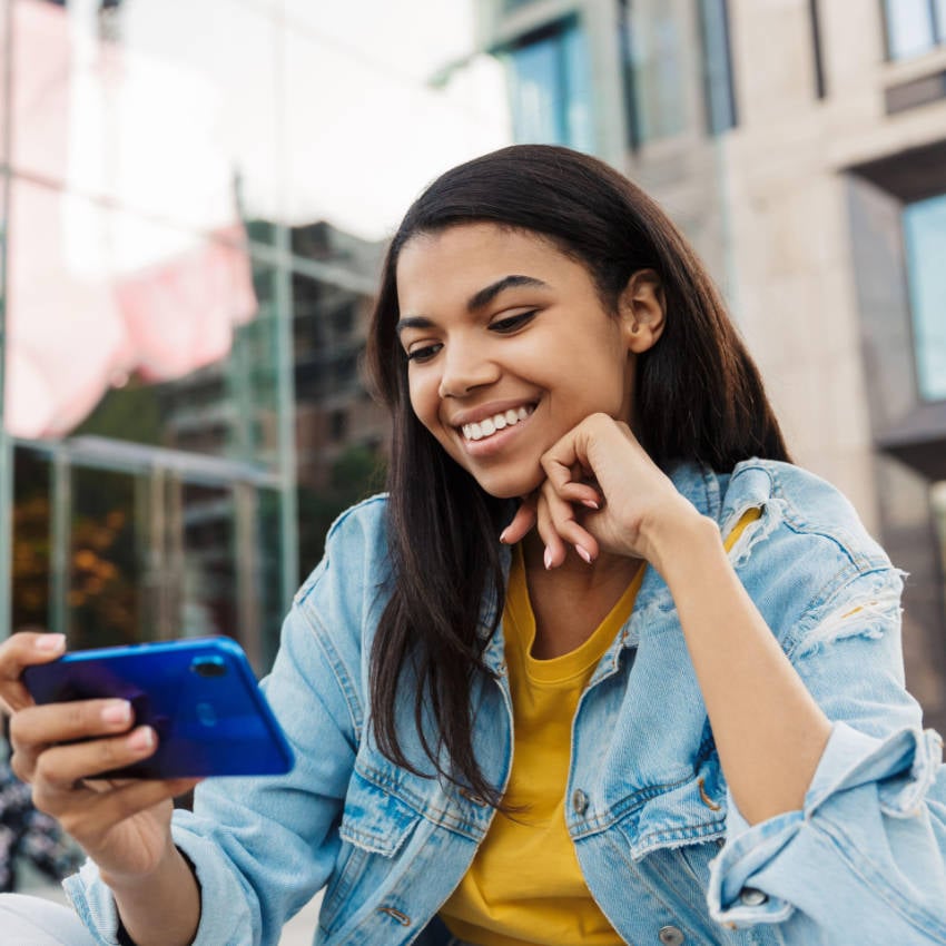 Teenager schaut lächelnd auf sein Handy