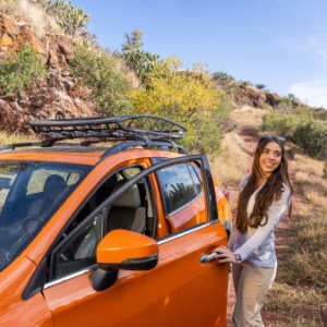 checkliste-auto_300x300_2024_04 Eine Frau öffnet eine Autotür eines orangenen Autos