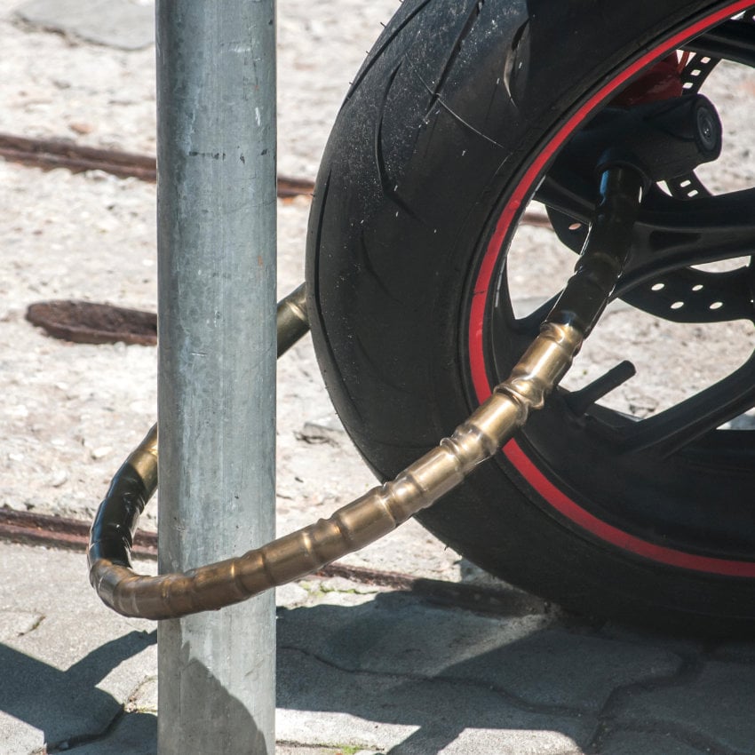 Nahaufnahme eines an einen Laternenpfahl angeschlossenen Motorrad-Vorderrads