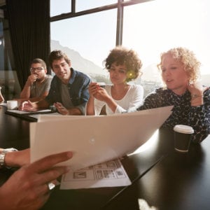 Nahaufnahme der Hände eines jungen Mannes, der anderen Menschen ein Dokument erläutert