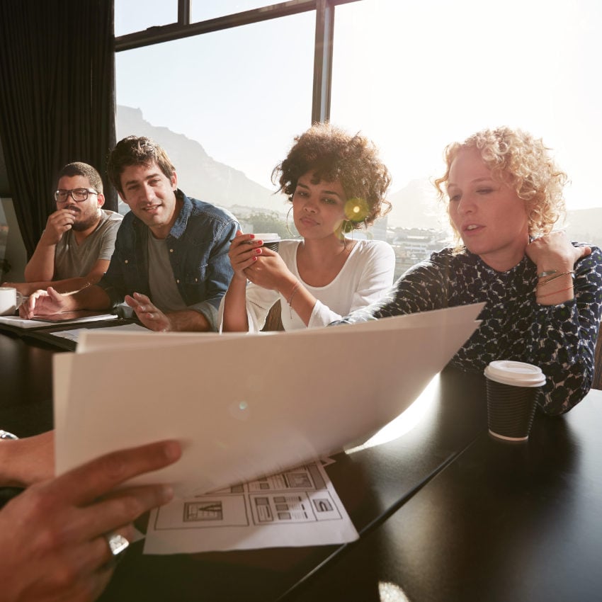 Nahaufnahme der Hände eines jungen Mannes, der anderen Menschen ein Dokument erläutert