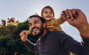 Mann trägt Jungen auf seinen Schultern