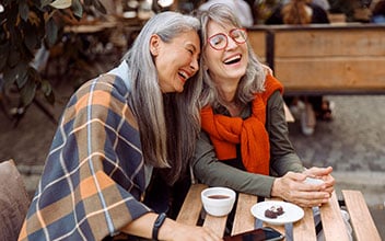 Zwei Frauen lachen herzlich miteinander