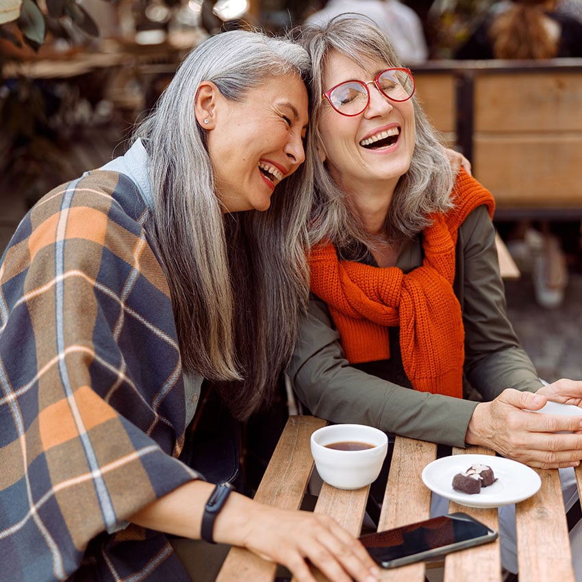 Zwei Frauen lachen herzlich miteinander