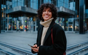 junge Frau hält ihr Smartphone in der Hand und lächelt