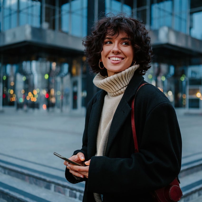 junge Frau hält ihr Smartphone in der Hand und lächelt