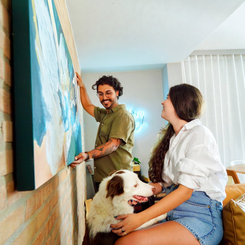 Colombia_woman_work_carmentrianaa Mann hängt Bild an Wohnzimmerwand auf