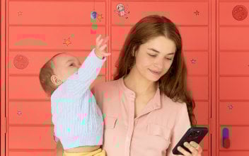 hausrat-versichert_352x220_2024_03 Junge Frau mit Kleinkind auf dem Arm schaut auf ihr Handy