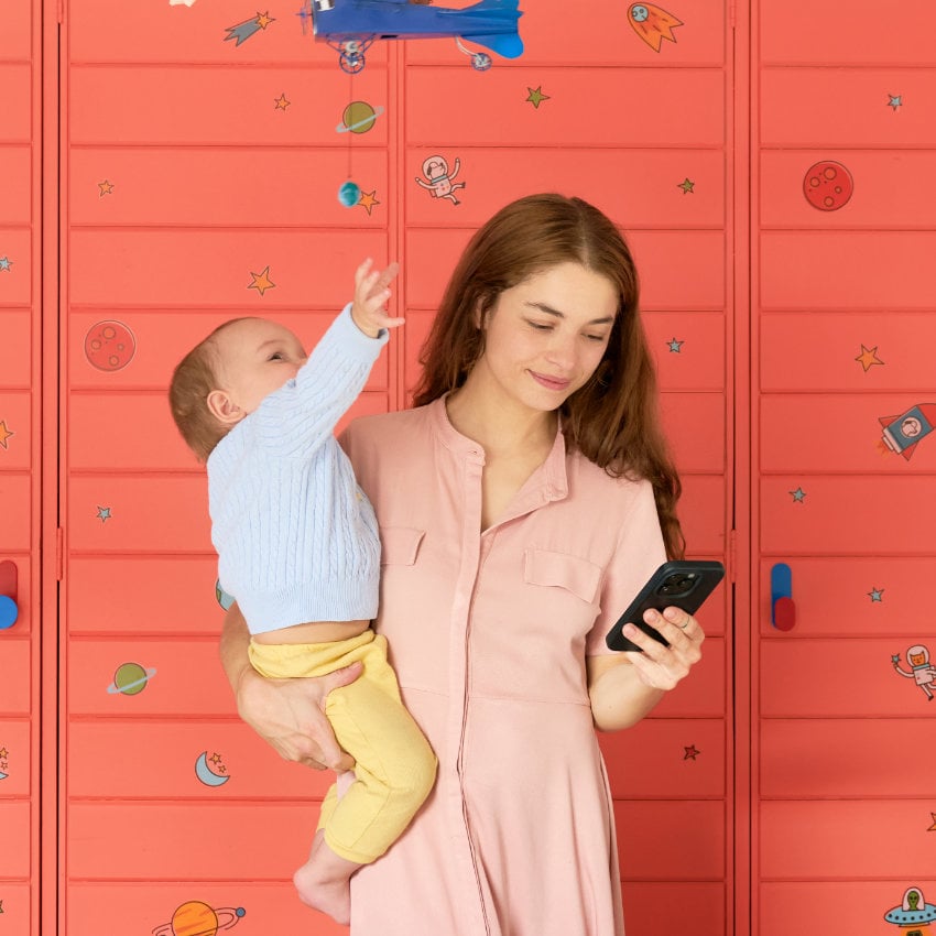 Colombia_mother_baby_mobile_carmentrianaa Junge Frau mit Kleinkind auf dem Arm schaut auf ihr Handy