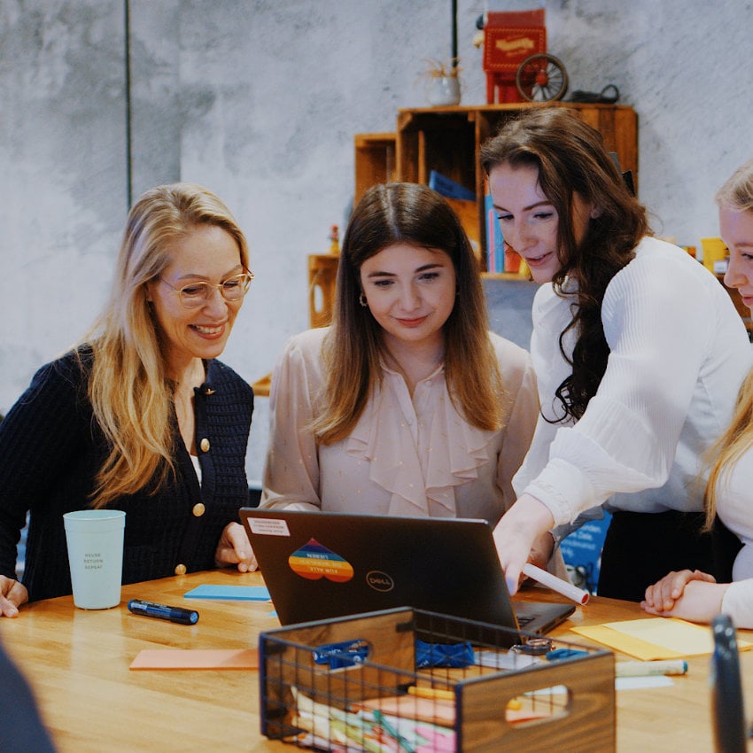 3 Frauen blicken auf einen Laptop