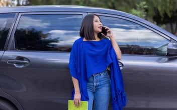 kfz-vergleich_352x220_2024_03 Frau steht neben ihrem Auto und telefoniert mit dem Handy