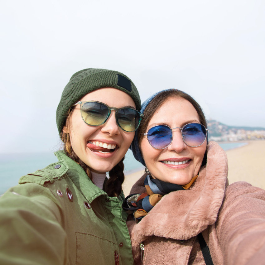Mutter und Tochter nehmen am Strand Selfie von sich auf