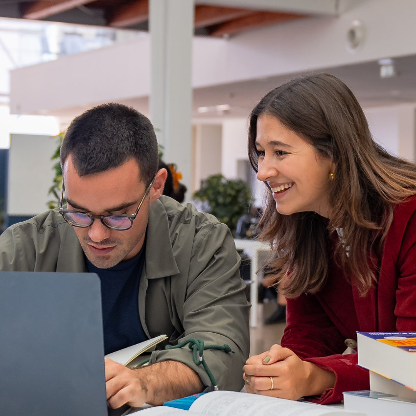 Lächelnde Frau schaut an Laptop arbeitendem Mann über die Schulter