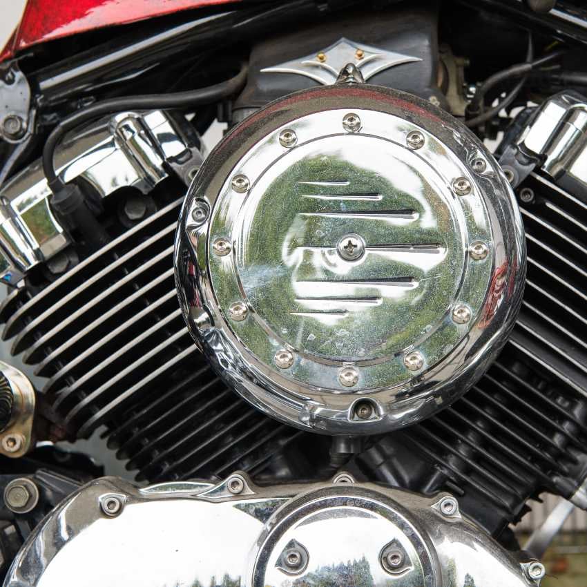 DSC_3438 Frau mit Sonnenbrille sitzt vor einem roten Motorrad auf einer Straße im herbstlichen Wald