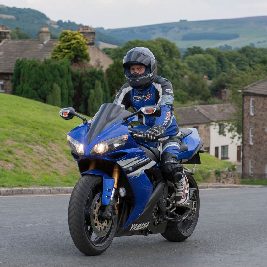 DDTEW9 Motorradfahrer fährt in Motorradmontur über eine Landstraße