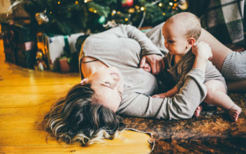 Mutter spielt auf einem Teppich mit ihrem Baby