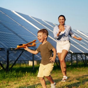 Mutter und Sohn spielen vor Solaranlage Mutter und Tochter spielen vor einer Solaranlage mit einem Spielzeugflugzeug