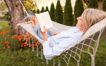 Frau liest entspannt ein Buch in der Hängematte