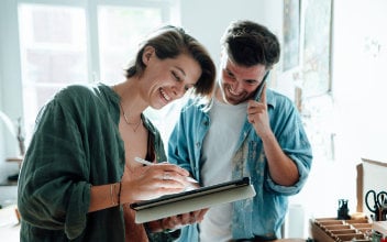 Telefonierender Mann mit Frau, die am Pad arbeitet Telefonierender Mann mit Frau, die am Pad arbeitet
