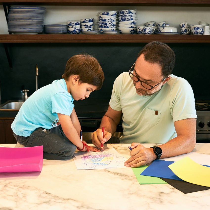 Mann mit seinem Sohn beim Malen am Küchentisch Mann mit seinem Sohn beim Malen am Küchentisch