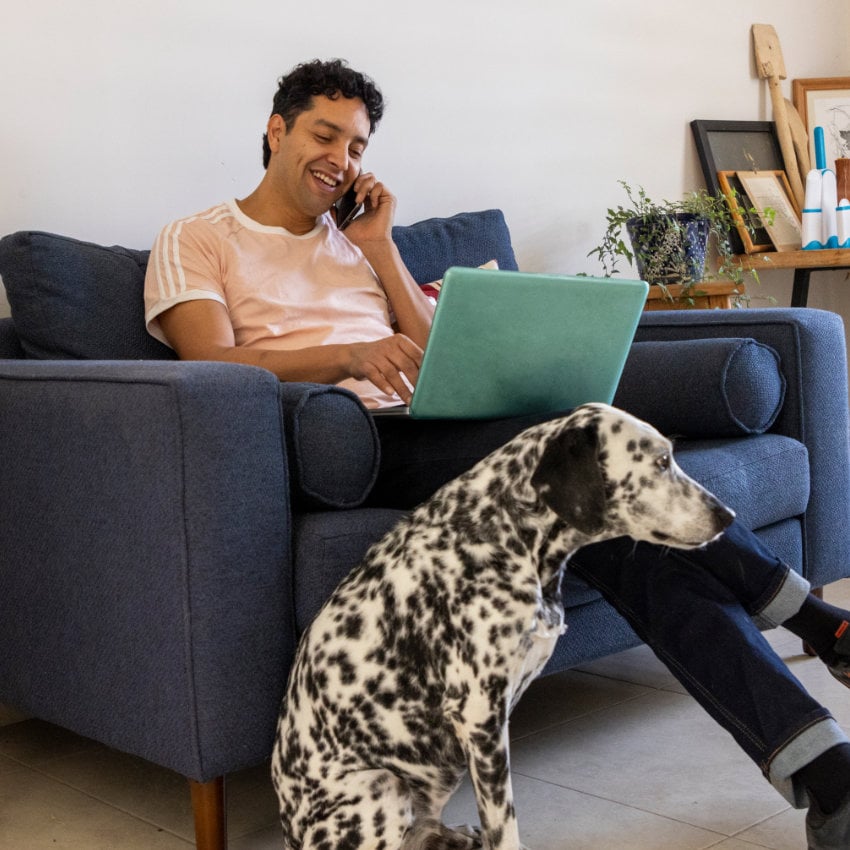 Mexico_man_home_work_laptop_mobile Mann telefoniert auf seinem Sofa, zu seinen Füßen sitzt ein Dalmatiner