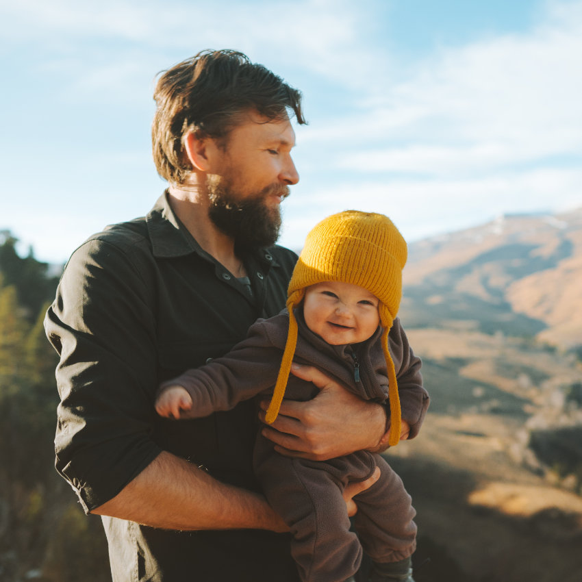 Mann in den Bergen mit Baby auf dem Arm