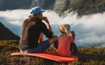 Vater und Tochter blicken über nebelverhangenes Tal in den Bergen