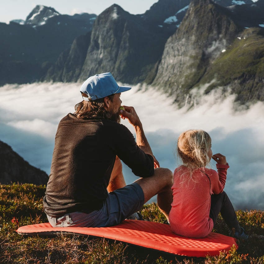 Vater und Tochter blicken über nebelverhangenes Tal in den Bergen