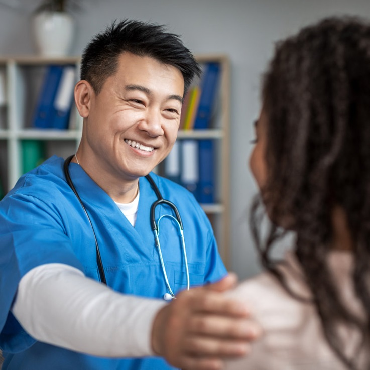 Lächelnder Arzt legt Patientin die Hand auf die Schulter
