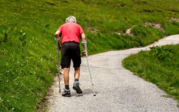 unfallversicherung-sinnvoll_352x220_2023_05 Mann mit Krücken müht sich einen Berg hinauf