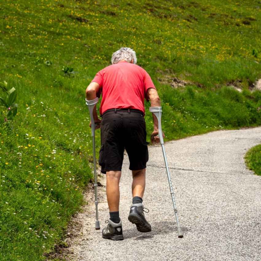 Mann mit Krücken müht sich einen Berg hinauf