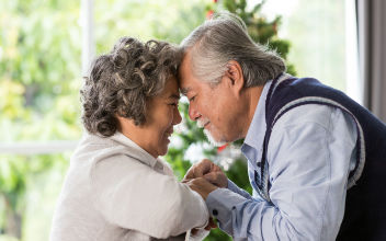 Asiatisches älteres Paar hält sich an den Händen und lehnt Stirn an Stirn