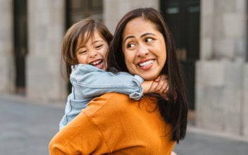 Lächelnde Frau trägt Kind auf dem Rücken Lächelnde Frau trägt Kind auf dem Rücken