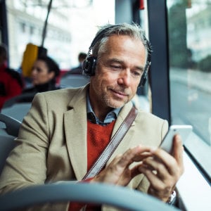 Mann mit Kopfhörer schaut auf sein Handy