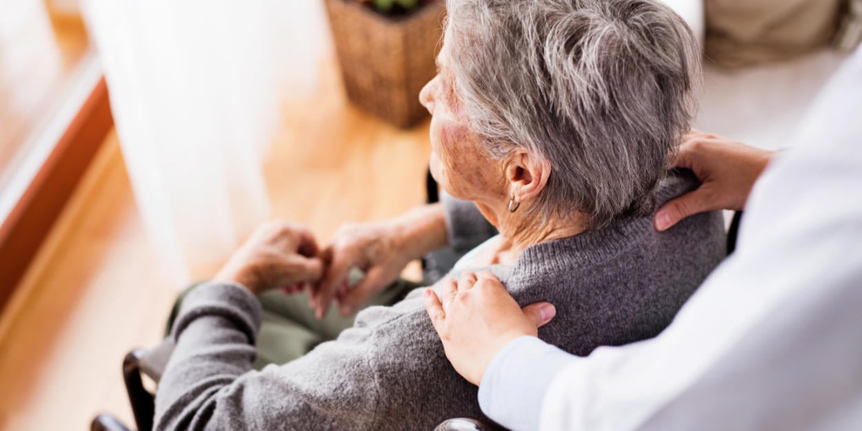 Frau massiert älterer Frau die Schultern