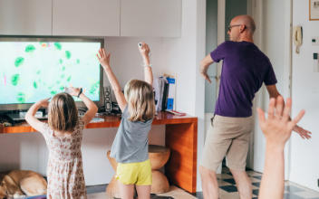 Vater tanzt mit Töchtern vor Fernseher