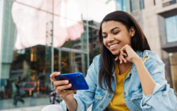Teenager schaut lächelnd auf sein Handy
