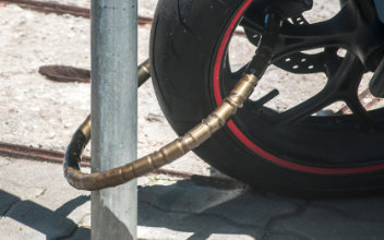 Nahaufnahme eines an einen Laternenpfahl angeschlossenen Motorrad-Vorderrads