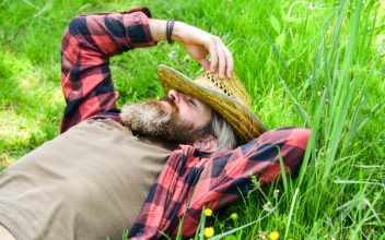 Mann mit Strohhut liegt im Gras