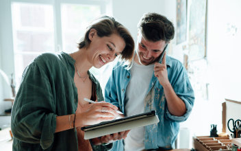 Telefonierender Mann mit Frau, die am Pad arbeitet