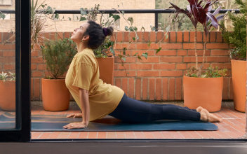 Frau beim Yoga auf ihrem Balkon