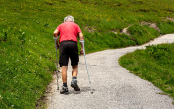 Mann mit Krücken müht sich einen Berg hinauf