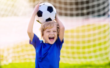 lachendes Kind hält Fußball in die Höhe