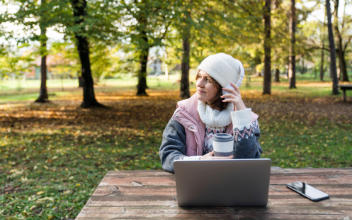 Freelancerin arbeitet im herbstlichen Wald an ihrem Laptop