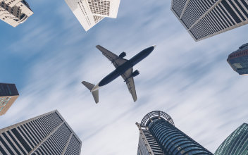 flug-stornieren_352x220_2025_01 Flugzeug über Wolkenkratzern