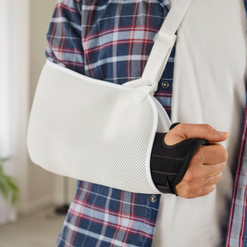 2H9PCA9_850x850 Nahaufnahme des Arms eines Mannes mit Stützkorsett und Schlingentuchverband nach einer Unfallverletzung