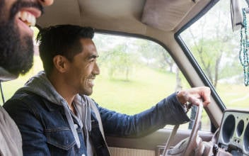 kfz-familienversicherung_352x220_2023_05 Zwei junge Männer beim Autofahren